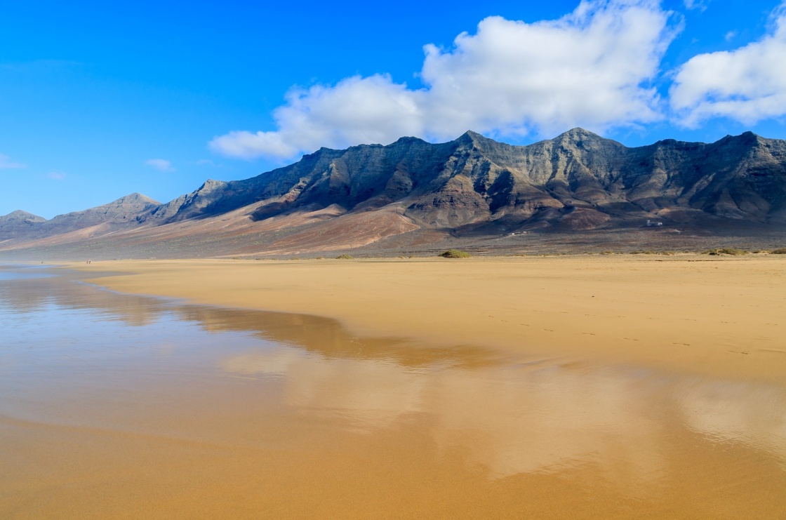 'Reflection of mountains in wet sand on Cofete beach in secluded part of Fuerteventura, Canary Islands, Spain' - Kanariansaaret